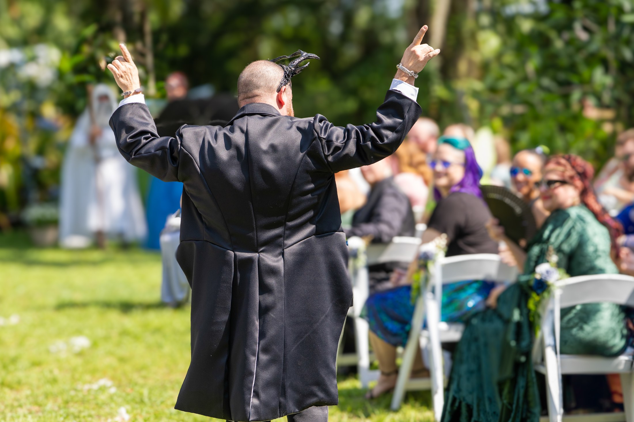 Newlywed raising both hands in celebration during an outdoor ceremony