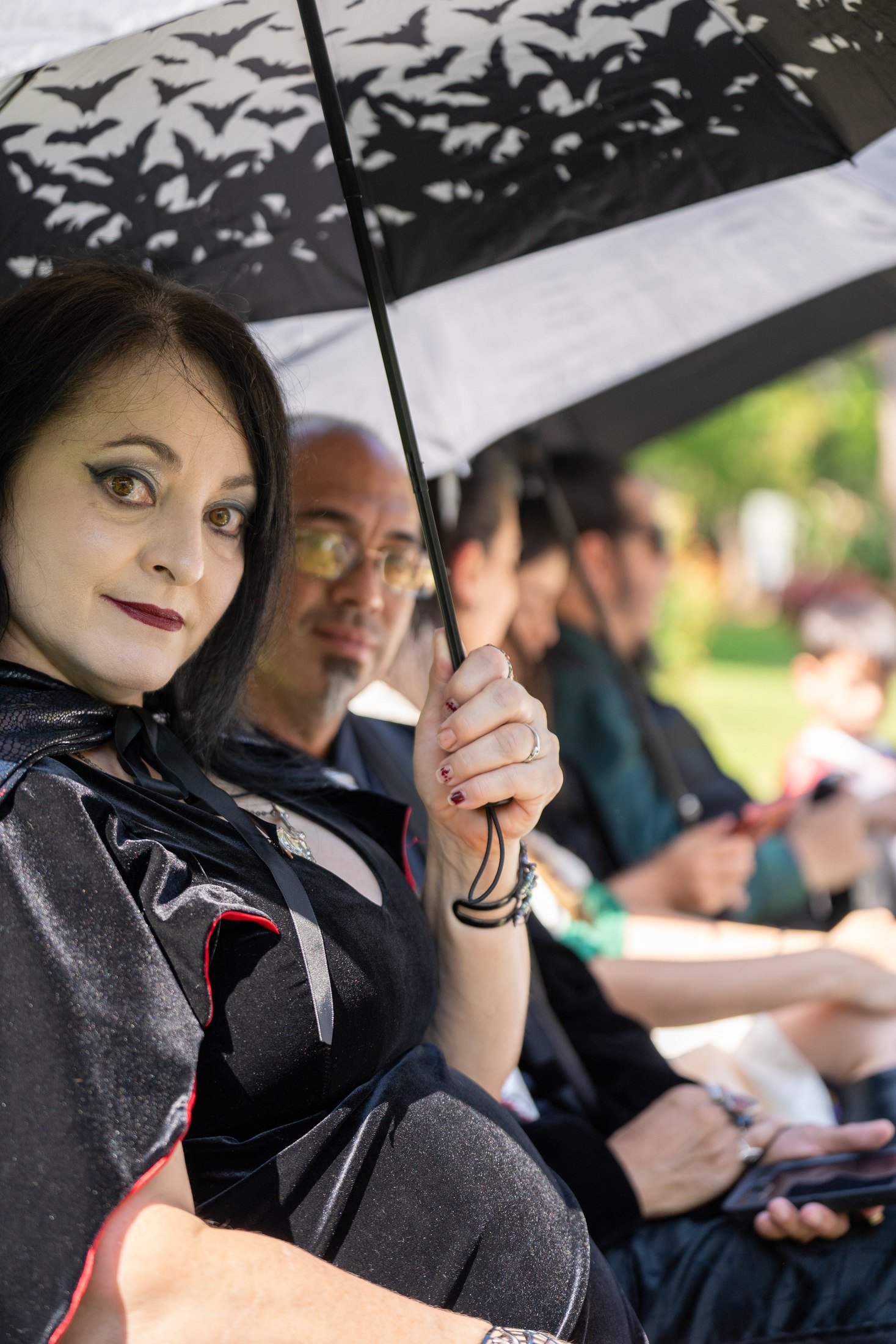 Wedding guest looking toward the camera beneath a patterned umbrella