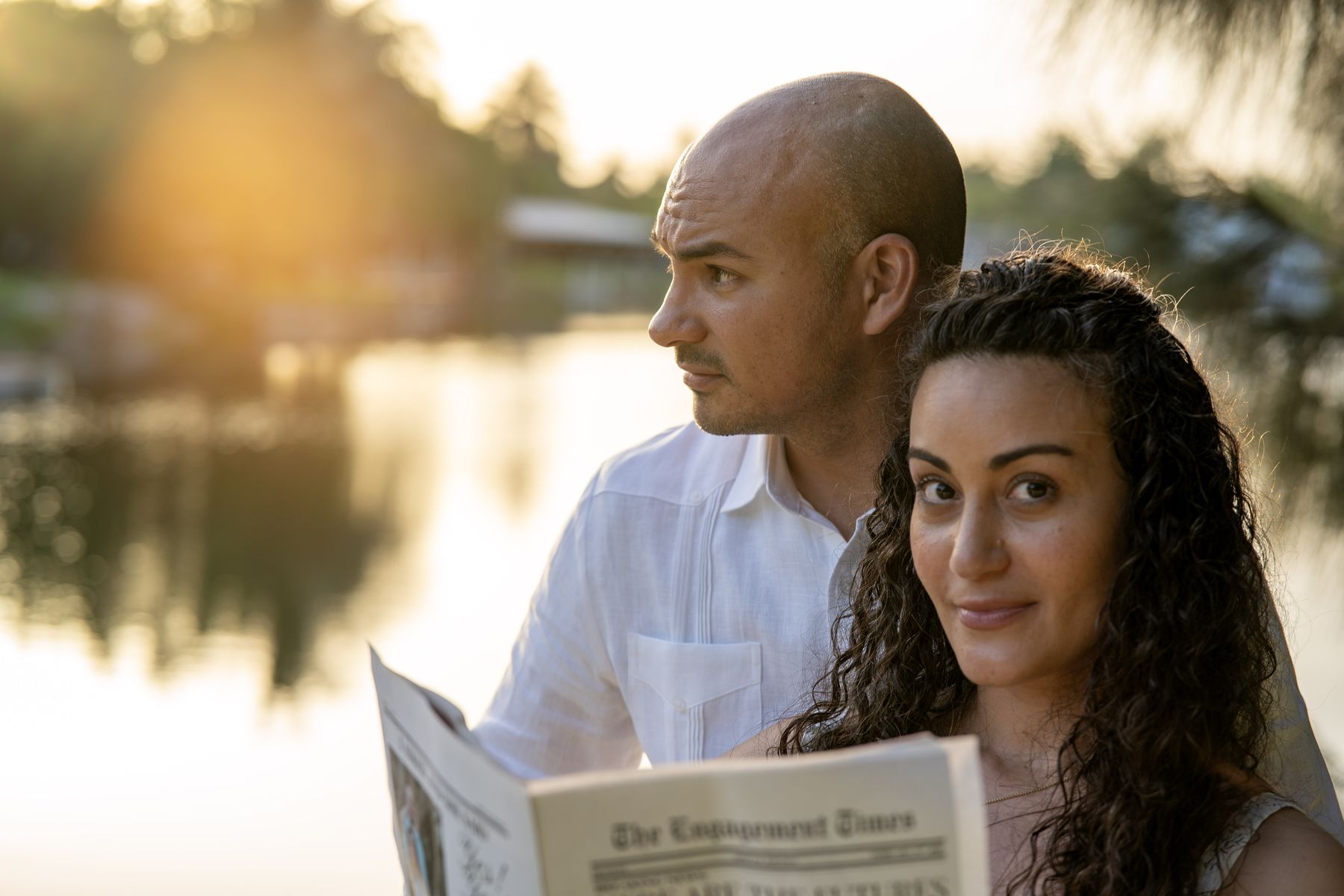 Couple posing together beside a lake at sunset