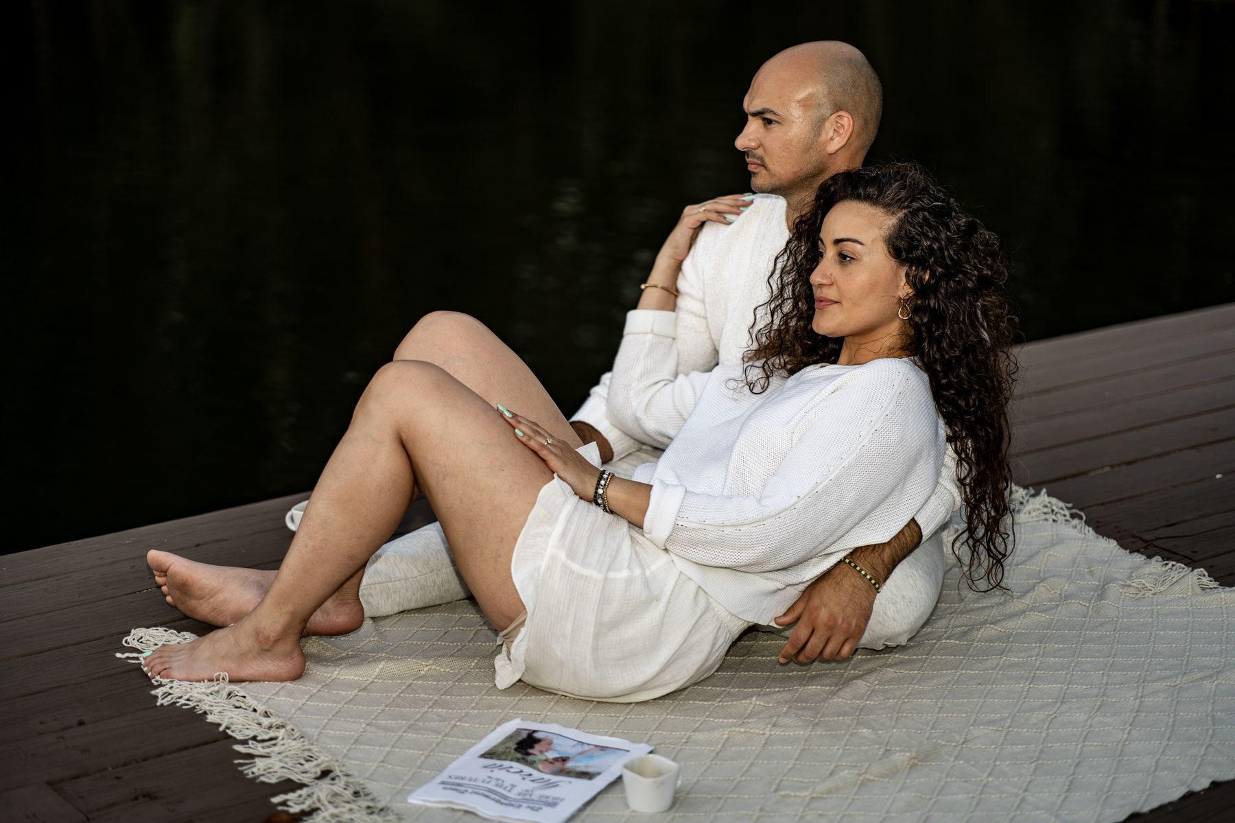 Couple reclining together on a blanket beside the water