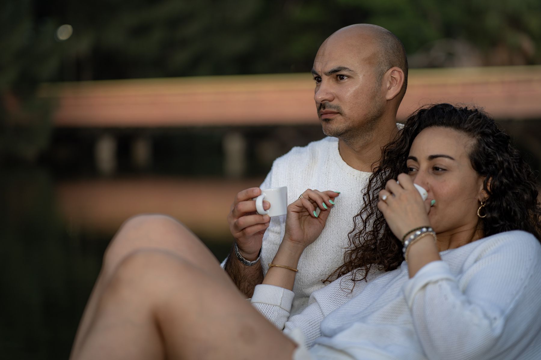 Couple sharing drinks while seated beside the lake