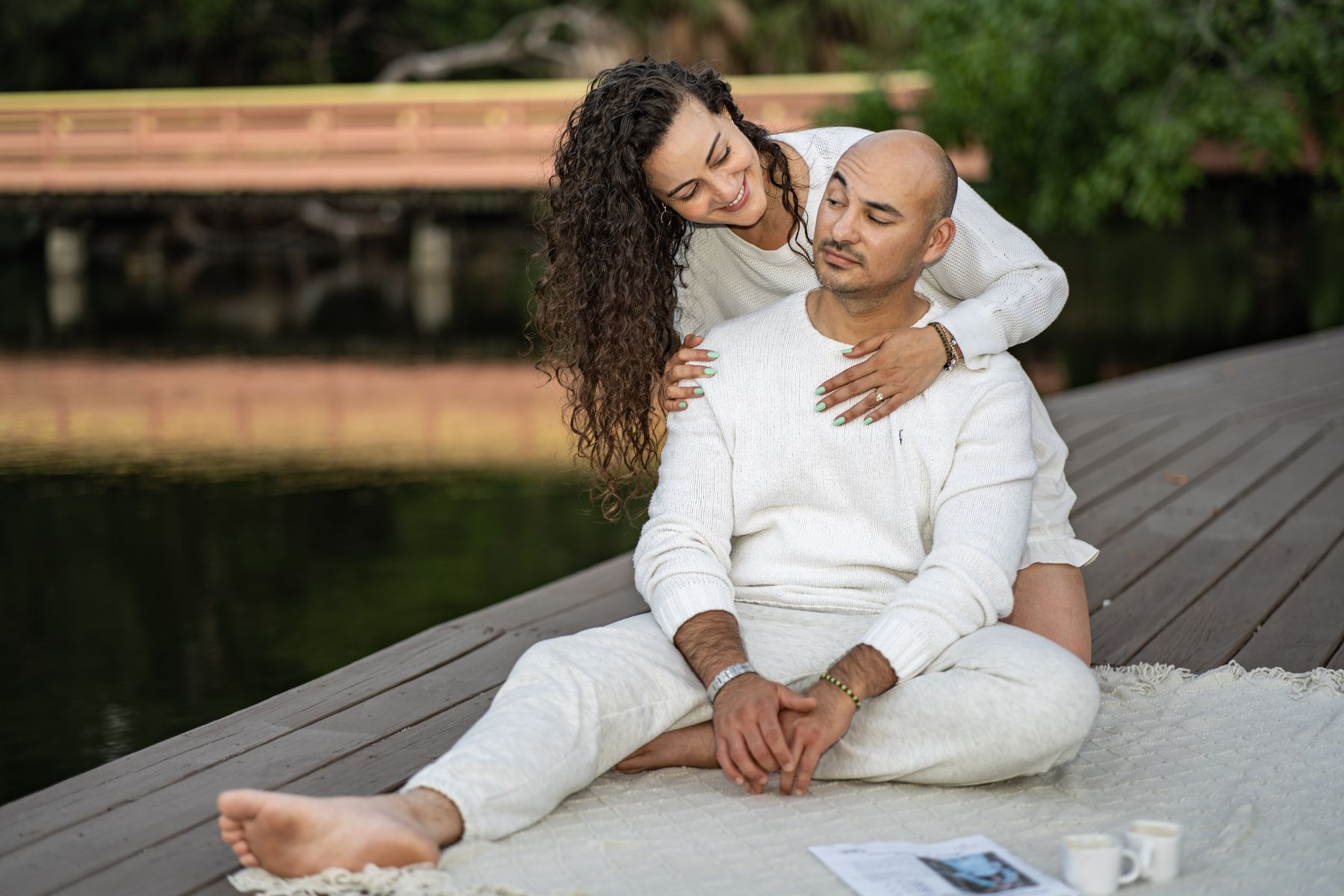 Woman wrapping her arms around her partner on a lakeside dock