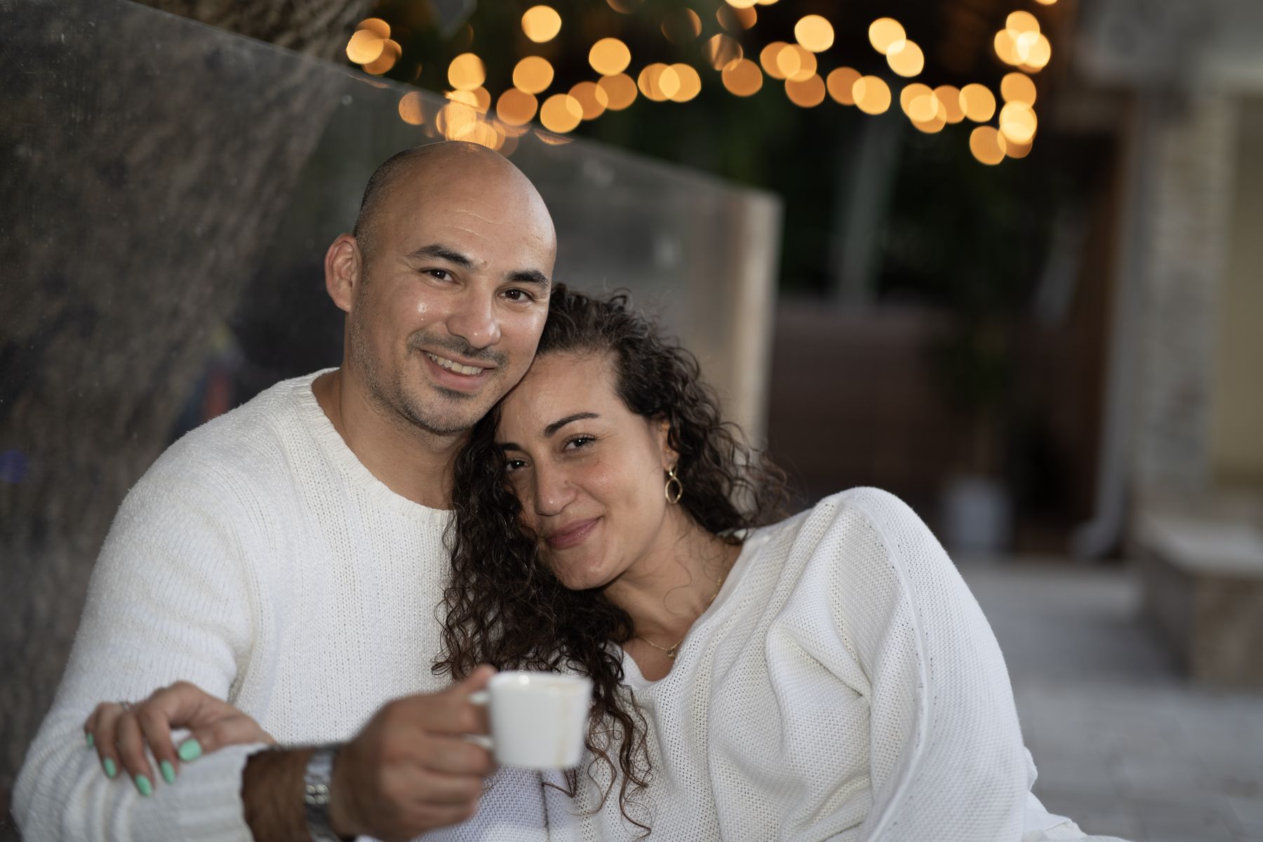 Couple smiling together beneath warm string lights