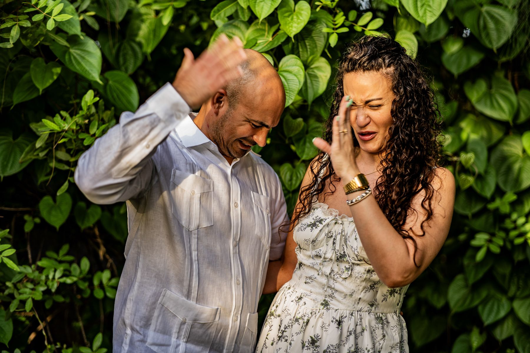 Couple laughing together among leafy trees