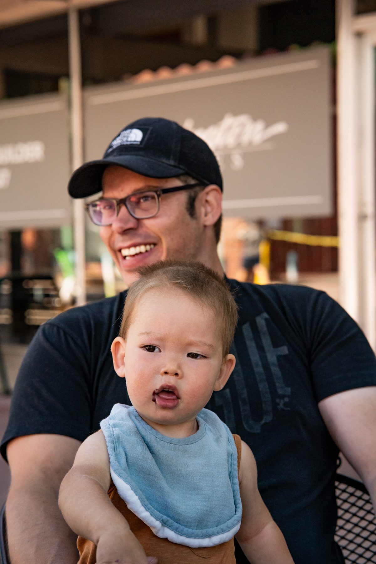 Smiling adult seated behind a toddler during an outdoor family outing