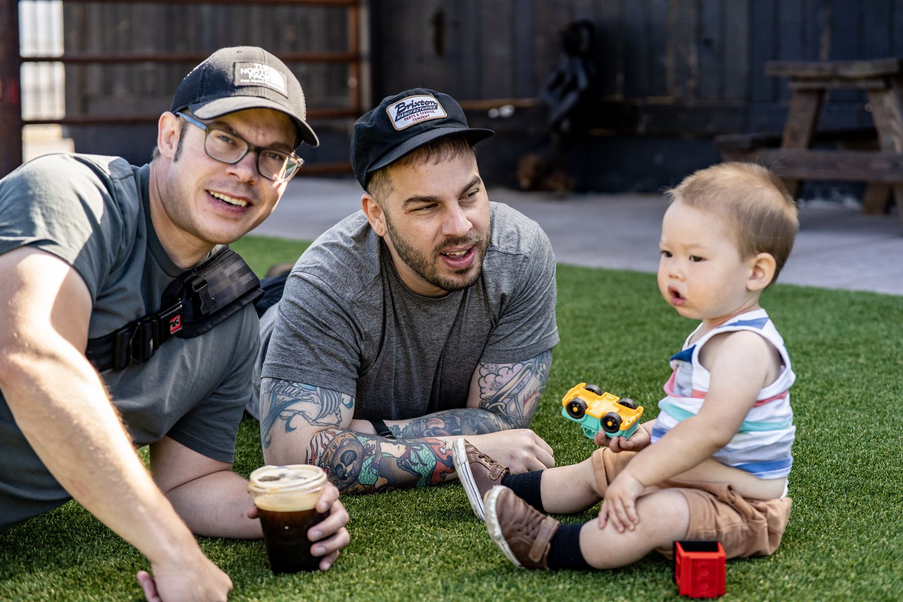 Two adults sitting with a toddler on grass