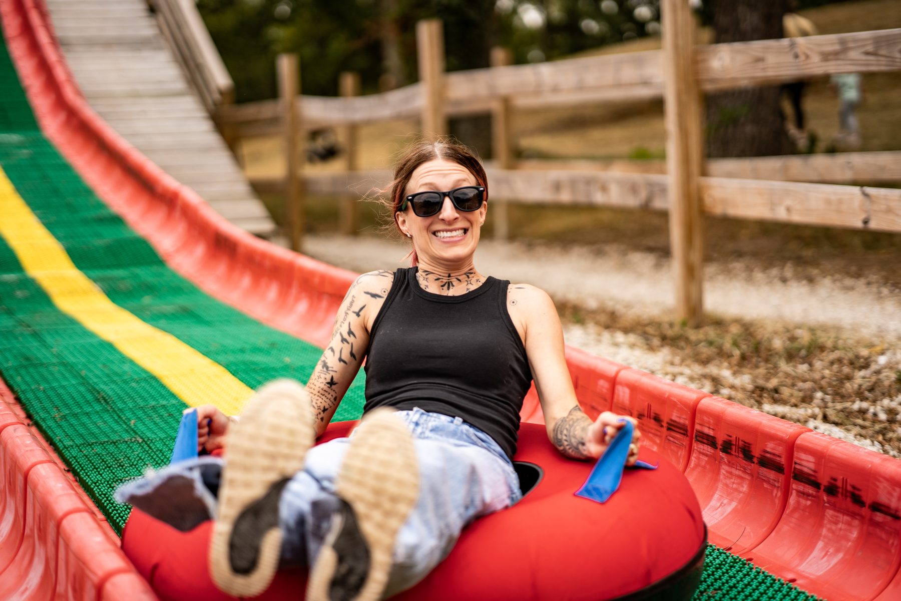 Tattooed woman laughing while riding a tube down a colorful slide