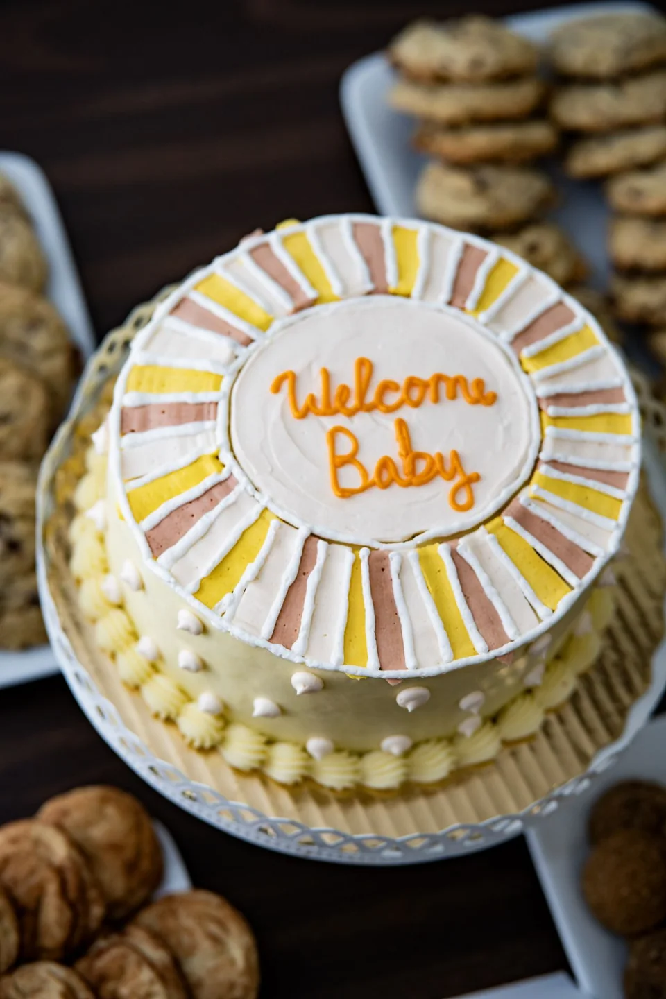 A decorated round cake with a Welcome Baby message
