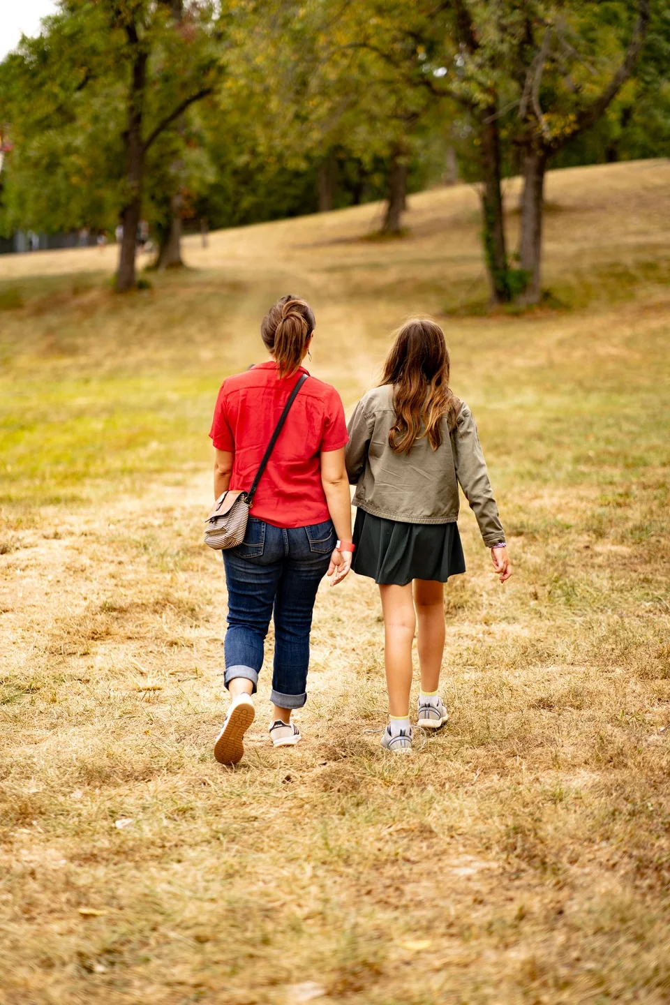 Mother and daughter holding hands while walking through a field