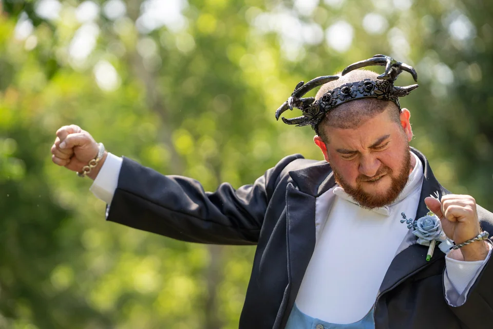 Groom celebrating as he walks down an outdoor wedding aisle