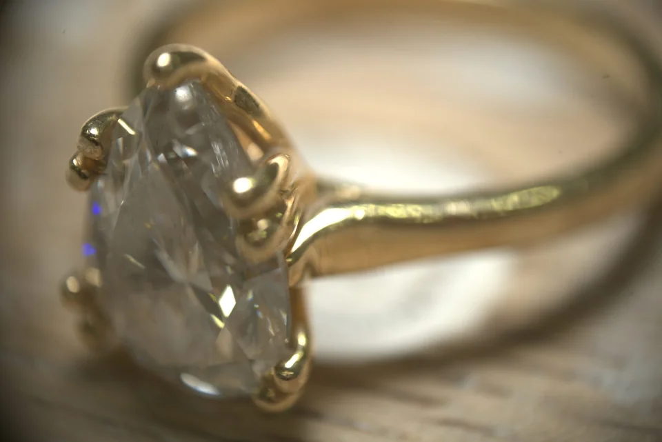 Side profile of a gold ring and clear faceted gemstone at extreme magnification