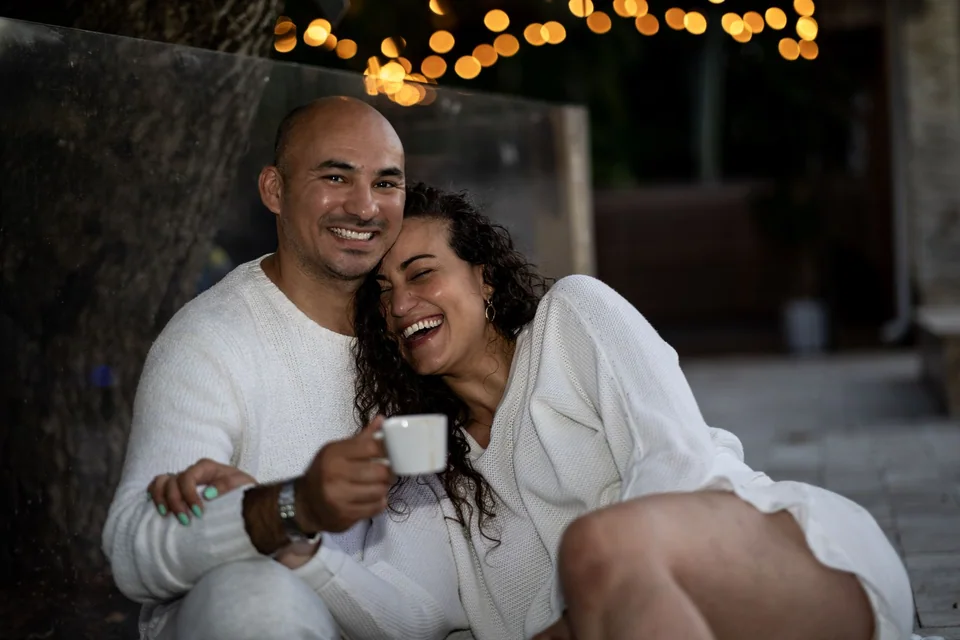 Couple laughing together beneath glowing string lights