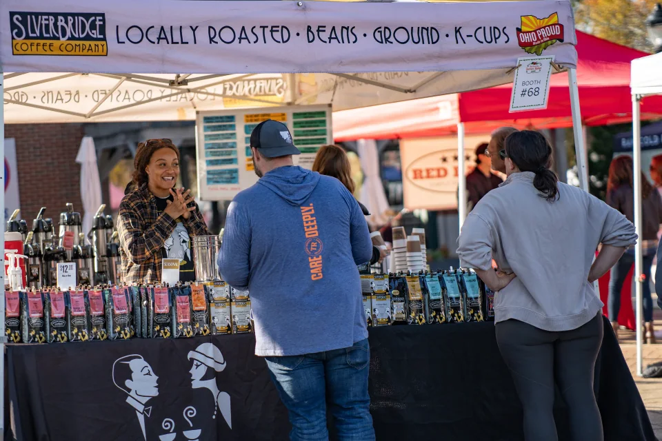 Shoppers gathered at a coffee stall with bottles and locally roasted beans