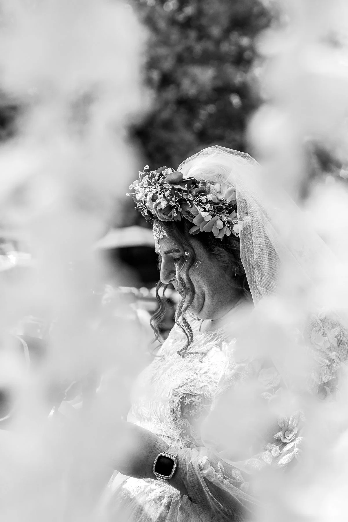 Black-and-white portrait of a bride framed by soft foreground blur