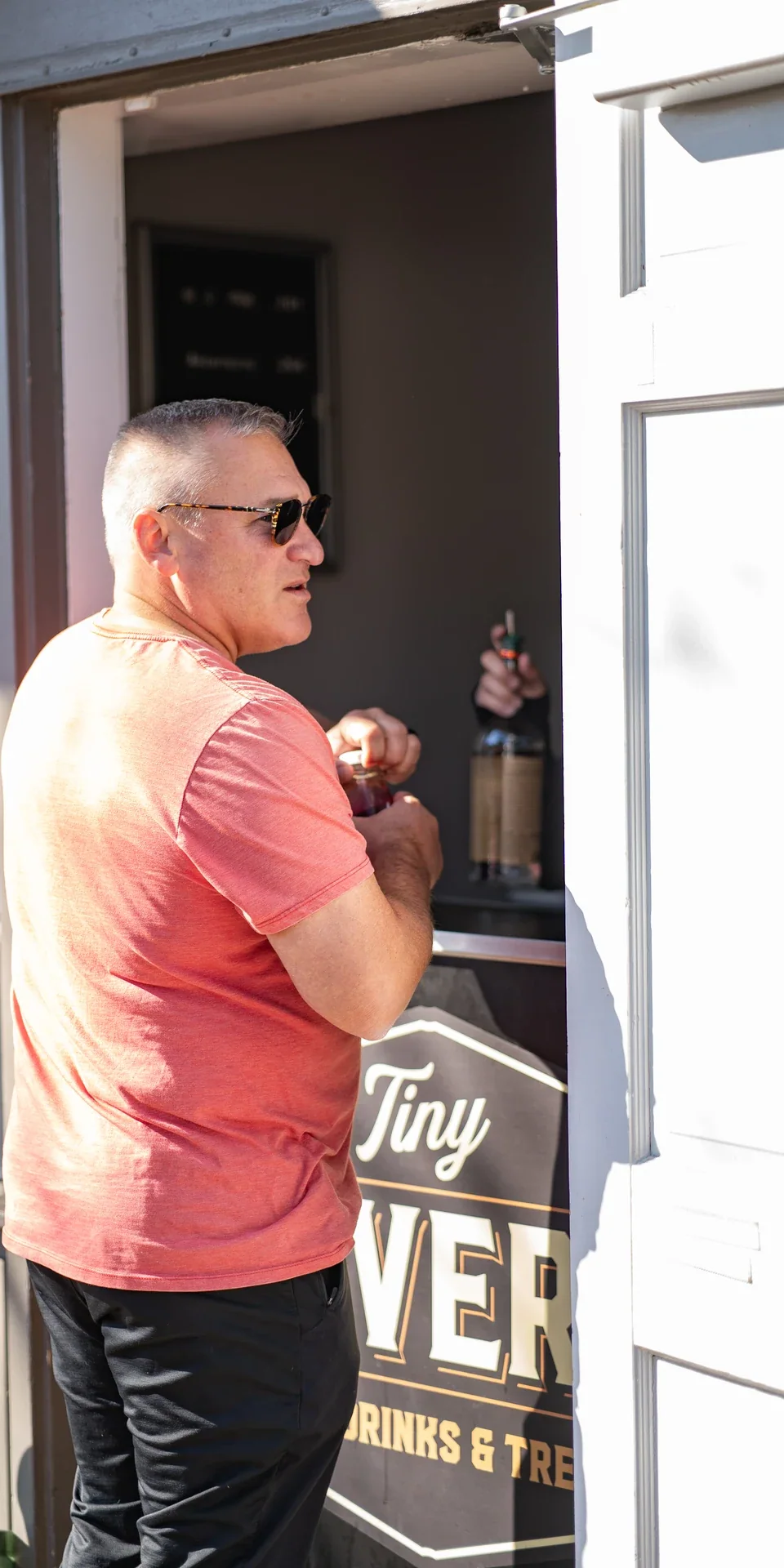 A person standing at an open doorway beside the sidewalk