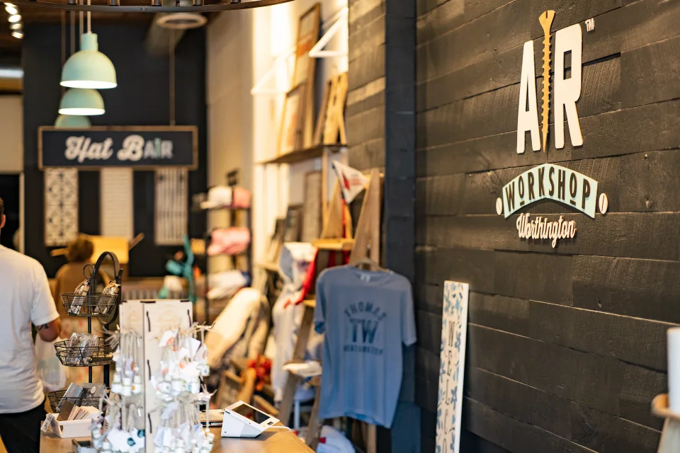 A warmly lit workshop entrance with a hat bar and retail displays