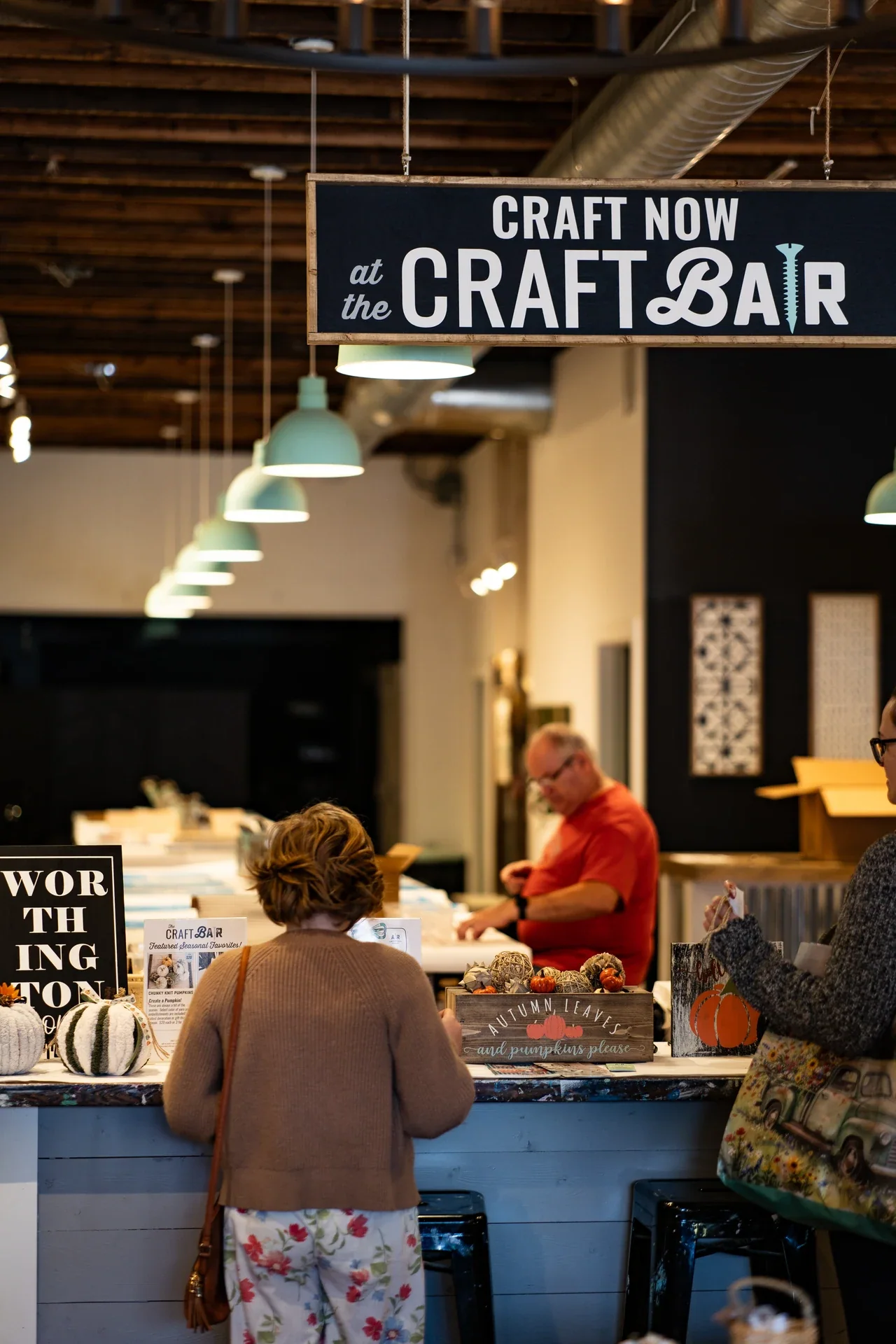 People inside a craft workshop beneath a Craft Now at the Craft Bar sign